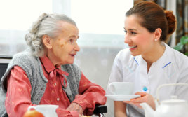 caregiver serving tea to an elderly woman